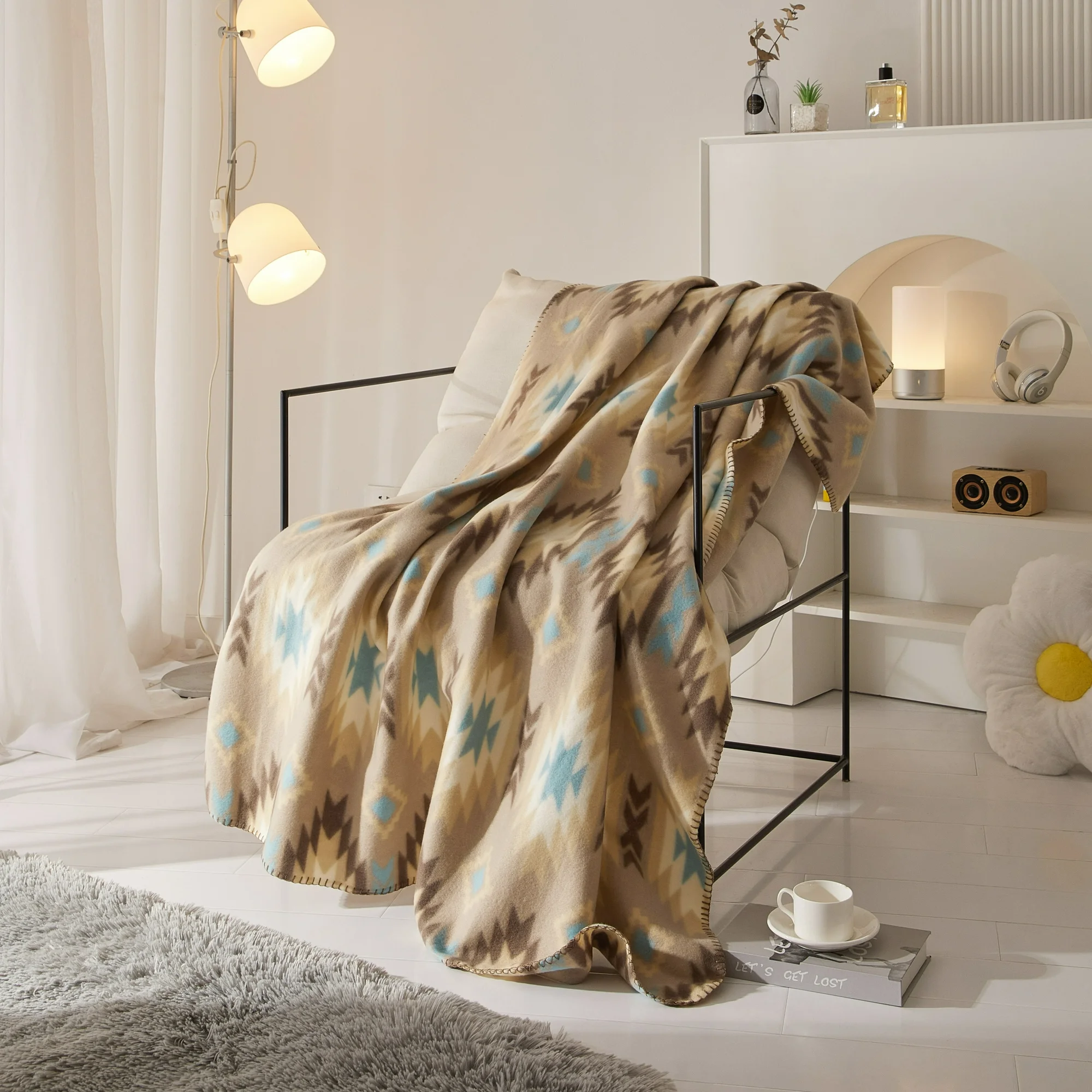 A beige patterned blanket draped over a bed frame in a stylish room with modern decor and furniture.