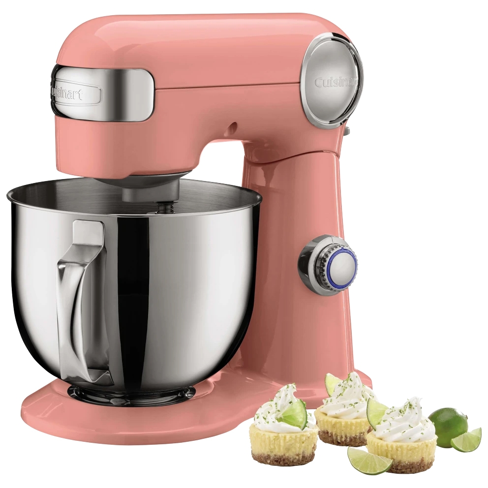 Pink stand mixer with a stainless steel bowl and control knob, displayed with three mini key lime cheesecakes on the side.
