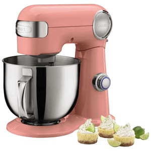 Pink stand mixer with a stainless steel bowl and control knob, displayed with three mini key lime cheesecakes on the side.