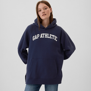 A model is wearing a navy blue hoodie with the text \“GAP ATHLETIC\“ in white capital letters, paired with denim jeans.