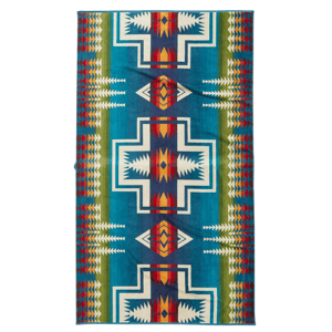 A colorful patterned blanket with geometric designs in blue, red, white, green, and orange tones, featuring bold lines and shapes arranged symmetrically.