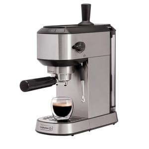 Calphalon Compact Espresso Machine with a sleek stainless steel finish, portafilter, and steam wand for frothing. A glass cup is placed under the spout, demonstrating its compact design.