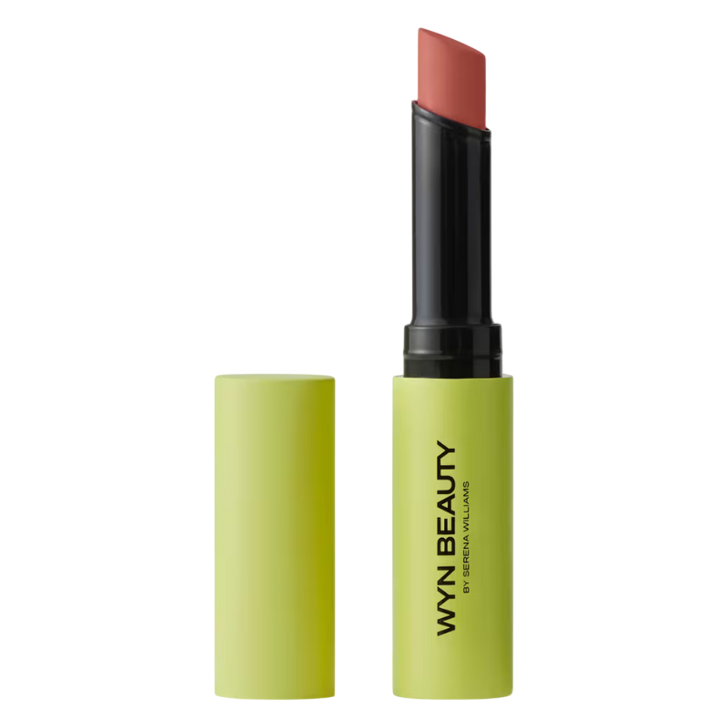 Lime green tube of WYN Beauty lipstick by Serena Williams, featuring a reddish hue with the cap off.