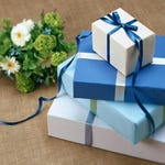 A bouquet of flowers next to stacked gift boxes with blue and white wrapping and ribbons.