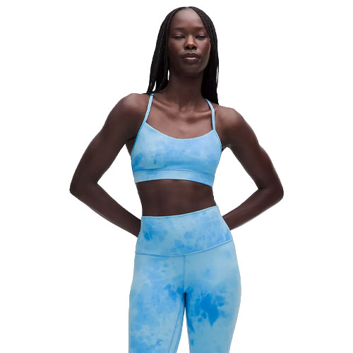 A woman models a blue tie-dye athletic outfit, including a sports bra and high-waisted leggings. The ensemble features a light and dark blue cloud-like pattern.