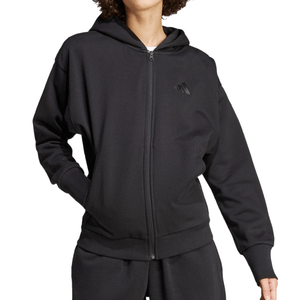 A person is wearing a black zip-up hoodie with a hood and elastic cuffs, featuring a subtle logo on the chest. They are also wearing matching black sweatpants.