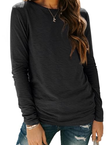 A person wearing a long-sleeved, dark-colored top paired with distressed jeans. The outfit includes simple jewelry like a necklace and bracelet.