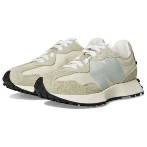New Balance Women's 327 Sneakers feature a retro-inspired design with a mix of suede and nylon materials in a light green color. They have white laces, a large \“N\“ logo, and a chunky black rubber sole for added traction.