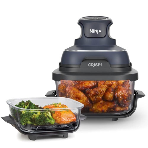 A Ninja food processor labeled \“CRISPi\“ is shown with prepared dishes, including buffalo wings and broccoli with salmon, in transparent containers.