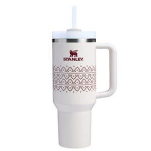 A white Stanley tumbler with a straw, featuring a handle and decorative patterns.