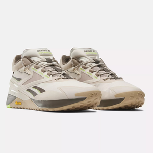 A pair of beige sneakers with neon accents and the Vibram logo visible on the sole.