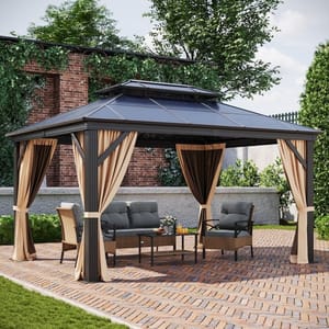A metal gazebo with a double-tiered roof and brown curtains, set on a brick patio, furnished with outdoor seating and a table.