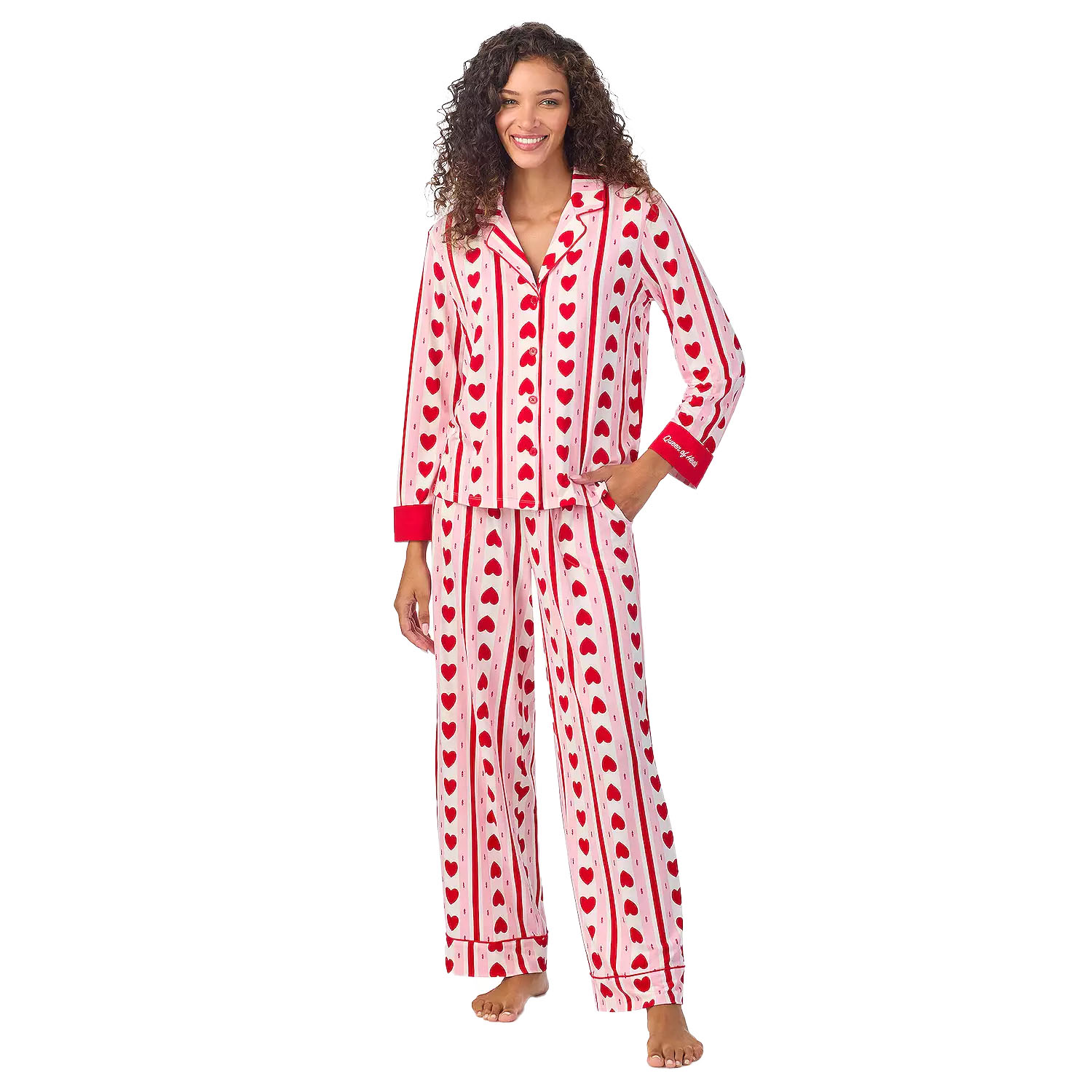 A woman is wearing a pajama set with red hearts and stripes on a white background. The set includes a long-sleeve top with red cuffs and matching wide-leg pants.