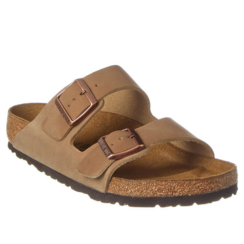 Birkenstock Arizona Leather Sandals feature two adjustable brown straps with copper buckles and a contoured cork footbed for support, set on a dark rubber outsole.