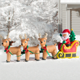 Inflatable Christmas decoration featuring Santa in a sleigh with three reindeer, set in a snowy landscape.