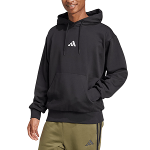 Man wearing a black hoodie with a small logo on the front, paired with olive green sweatpants featuring a similar logo.