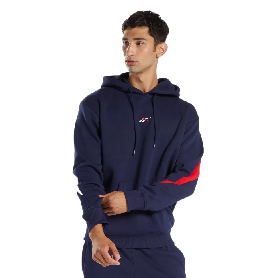 A person wearing a navy blue Reebok hoodie with a red stripe on the sleeve and matching navy pants. The hoodie features a small Reebok logo on the chest.