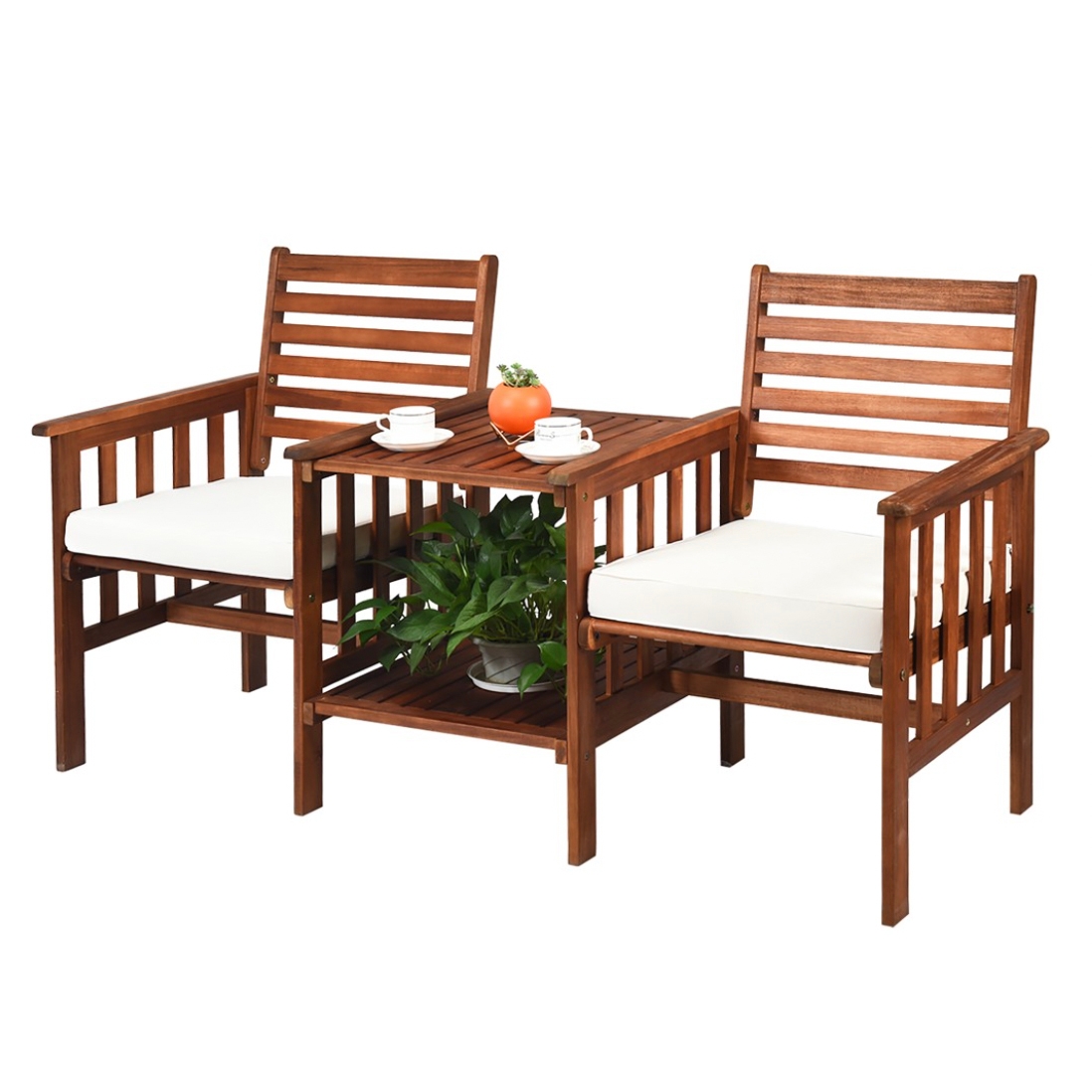 Acacia Wood Patio Set features two wooden chairs with slatted backs and armrests, attached by a central small table with a shelf underneath, holding a potted plant. The chairs have white seat cushions, and the table is set with cups and a decorative item.