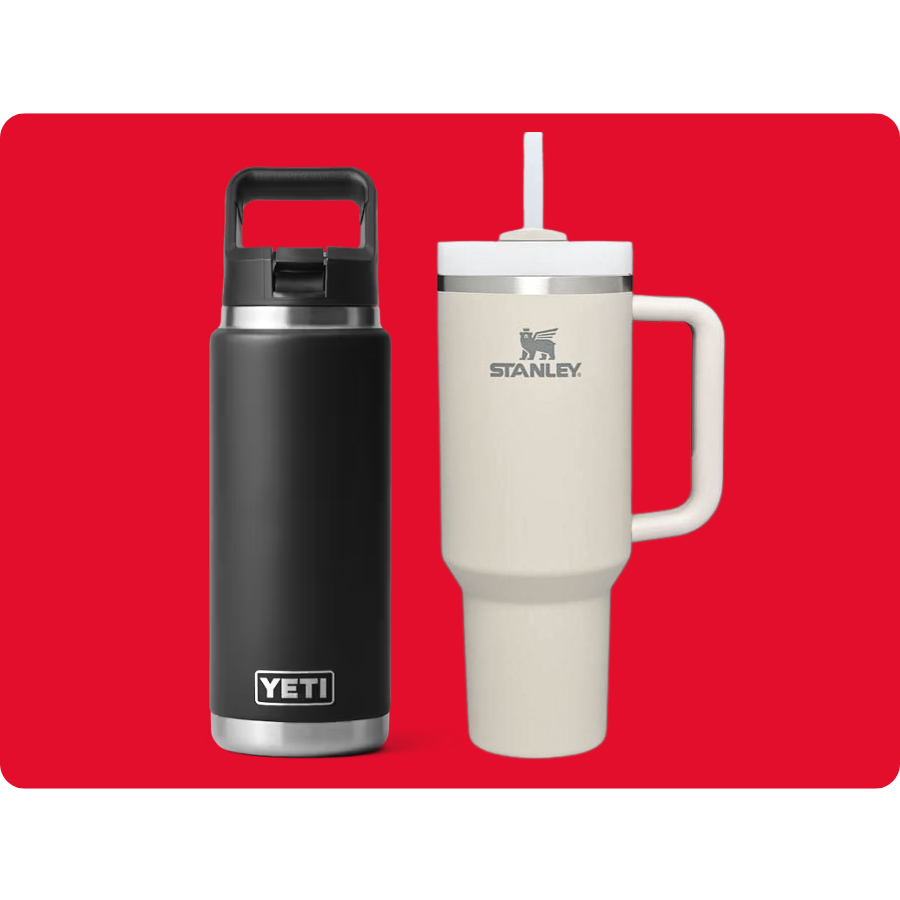 A black YETI bottle with a handle and lid sits next to a beige Stanley mug with a handle, lid, and straw, both on a red background.