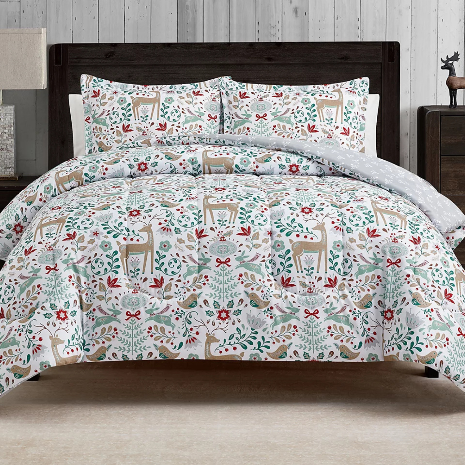 A festive 3-piece comforter set with a holiday theme featuring deers, birds, and floral designs in red, green, and beige on a white background. Includes a comforter and matching pillow shams, all with a rustic woodland pattern.
