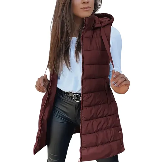 A woman is wearing a maroon quilted vest with a hood, over a white long-sleeve top and black leather-look pants, accessorized with a belt featuring a round buckle.
