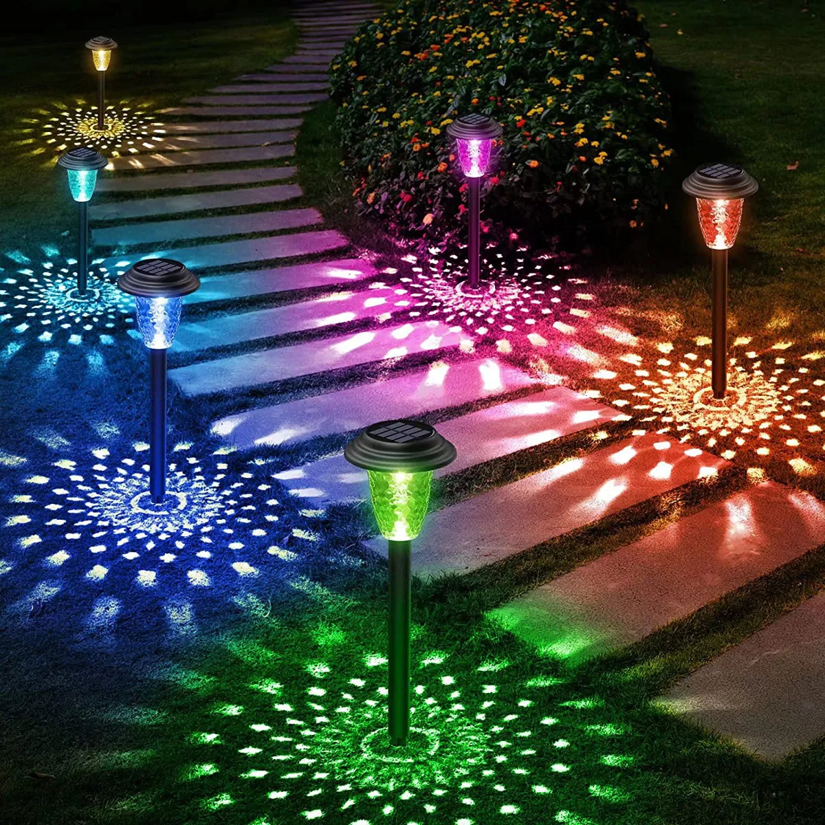 Colorful solar pathway lights illuminate a garden path, casting vibrant, patterned light on the ground with hues of blue, green, pink, and more.