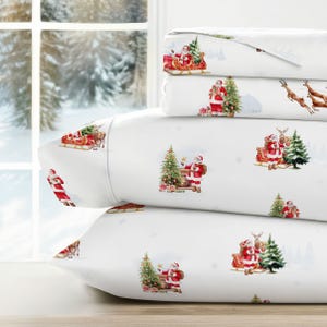Festive bedding set featuring Santa Claus, reindeer, and Christmas trees on a white background, with a snowy winter scene outside the window.
