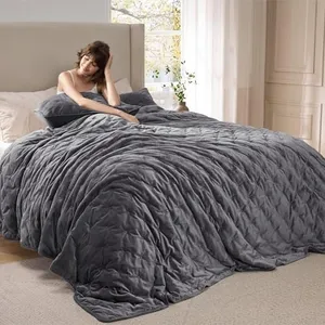 A gray velvet weighted blanket is draped over a bed with a person sitting up, holding a matching pillow.