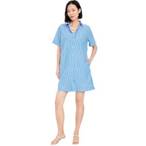 A woman is wearing a blue and white vertical striped shirt dress with short sleeves, a collar, and button-down front. She pairs it with white sandals.