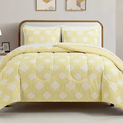 A bed features a comforter and pillowcases with a yellow geometric pattern on a white background. Two framed geometric prints hang on the wall above the bed.