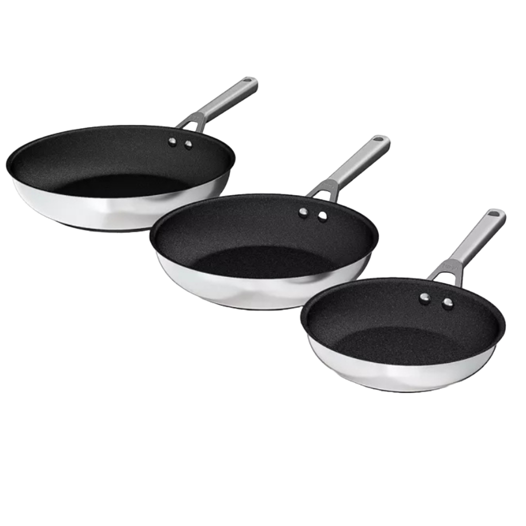 A 3-piece Ninja stainless steel nonstick frying pan set with brushed silver exteriors and black interiors, featuring sizes 8\“, 10.25\“, and 12\“ with double-riveted handles.
