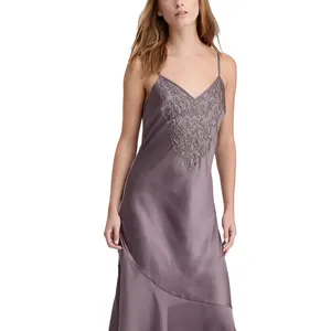 A woman is wearing a mauve satin slip dress with spaghetti straps and intricate embroidery detailing on the bodice.