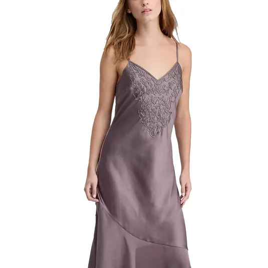 A woman is wearing a mauve satin slip dress with spaghetti straps and intricate embroidery detailing on the bodice.
