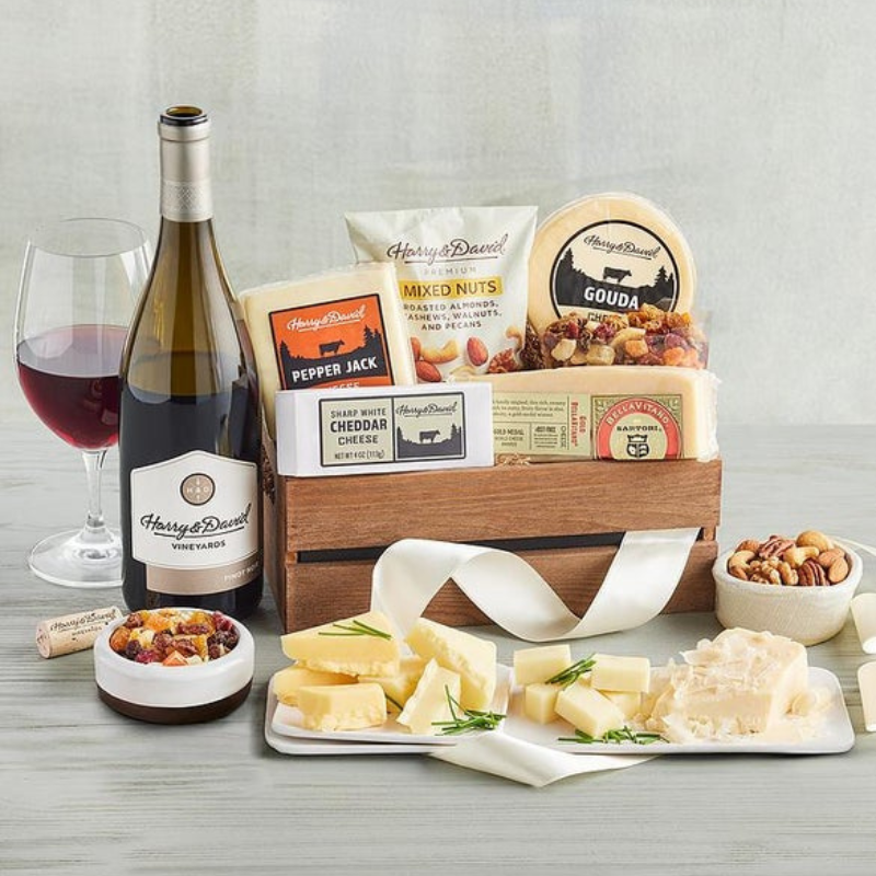 A Harry & David gift set featuring a bottle of wine, sharp white cheddar, pepper jack cheese, gouda, mixed nuts, and a selection of dried fruits.