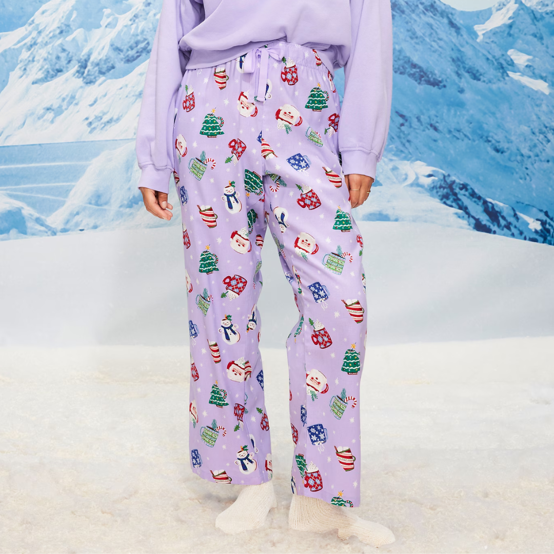 Purple pajama pants with festive holiday prints featuring Santa, snowmen, Christmas trees, and stockings.