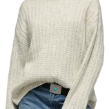 A person is wearing a cream-colored, ribbed knit sweater paired with blue jeans. The outfit features a distinctive belt buckle with a turquoise centerpiece.