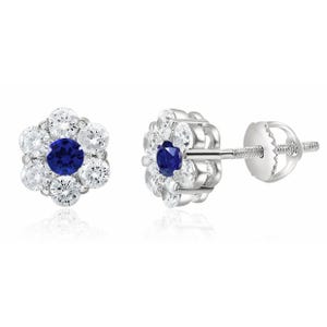 Silver stud earrings with a flower design, featuring a central round blue gemstone surrounded by six clear cubic zirconia stones.