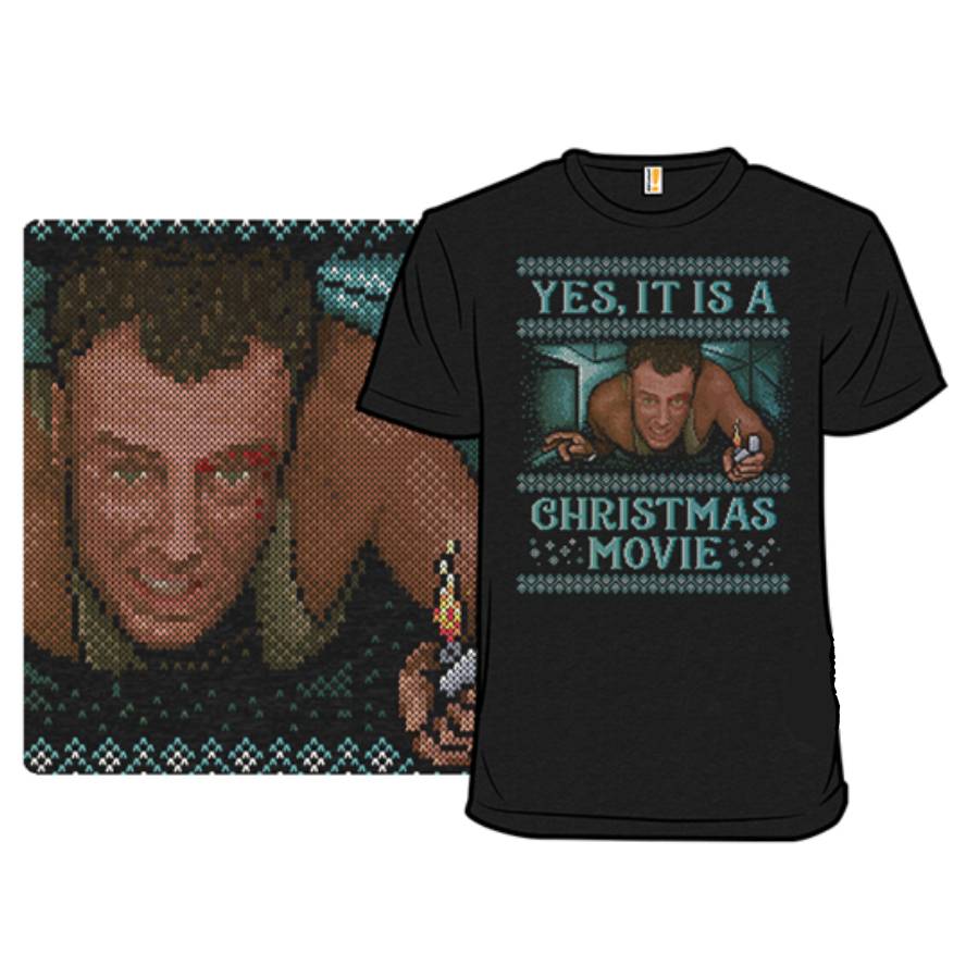 A black T-shirt featuring a pixelated image of a person crawling in a vent, holding a lighter, with the text \“Yes, it is a Christmas movie\“ above and below the image.