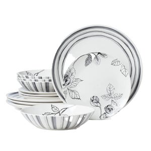 Stacked ceramic dinnerware set with black floral and stripe designs on white background, including bowls and plates.
