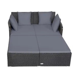 Rattan daybed with gray cushions and four pillows, designed for outdoor use. Suitable for lounging, its structure features a woven pattern and a sturdy frame.