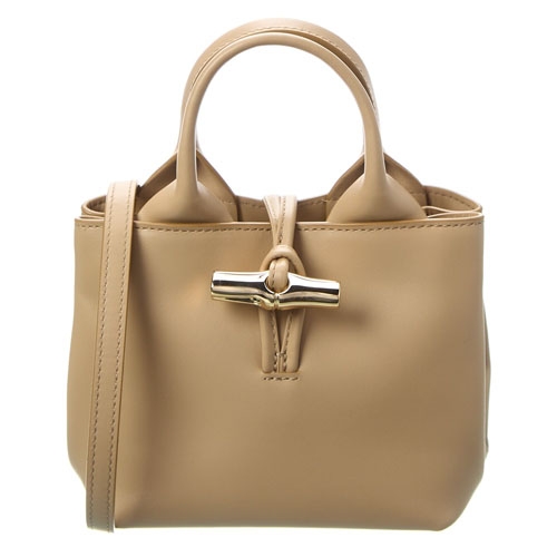 A compact beige leather handbag with short handles and a detachable strap, featuring a distinctive metallic clasp closure.