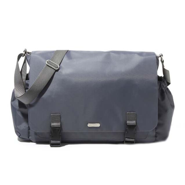 A dark gray Baggallini messenger bag with a large flap, adjustable shoulder strap, and two front buckles. It has elastic side pockets and a small metal logo plate on the front.