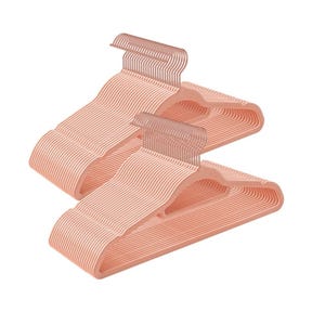 A set of light pink, velvet non-slip hangers with silver hooks stacked in two piles.