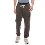 A person wearing dark gray jogger pants with a white drawstring and white sneakers, featuring a black waistband with white text.