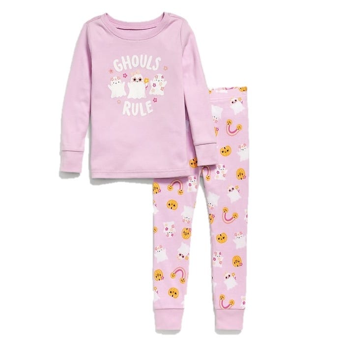 Pink children's pajama set with a long-sleeve top featuring \“Ghouls Rule\“ and ghost illustrations. The pants have a matching pattern with ghosts, rainbows, and smiling pumpkins.