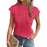 A woman wears a textured pink short-sleeve top paired with denim shorts and holds a tan clutch.