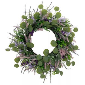 A round wreath featuring a mix of artificial greenery with eucalyptus leaves, purple flowers, and lavender accents, creating a lush, natural appearance.