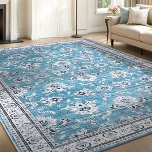 A large blue and white floral-patterned area rug is placed in a living room setting with a sofa, pillows, and a floor lamp in the background.
