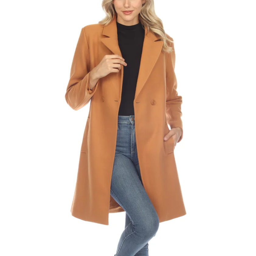 A woman is wearing a caramel-colored coat over a black top and blue jeans, paired with black ankle boots.