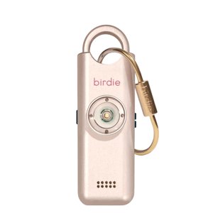 A gold-colored personal safety alarm with the word \“birdie\“ on it, featuring a loop for attachment, a prominent button, and a small speaker grill.
